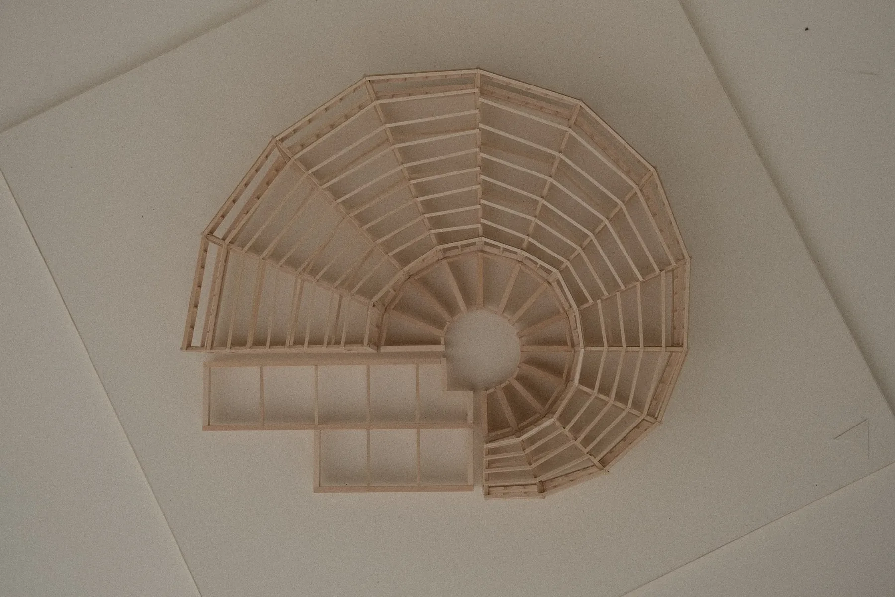 Model photographed from overhead, showing the roof structure fanning out from a central circular void across a polygonal plan.
