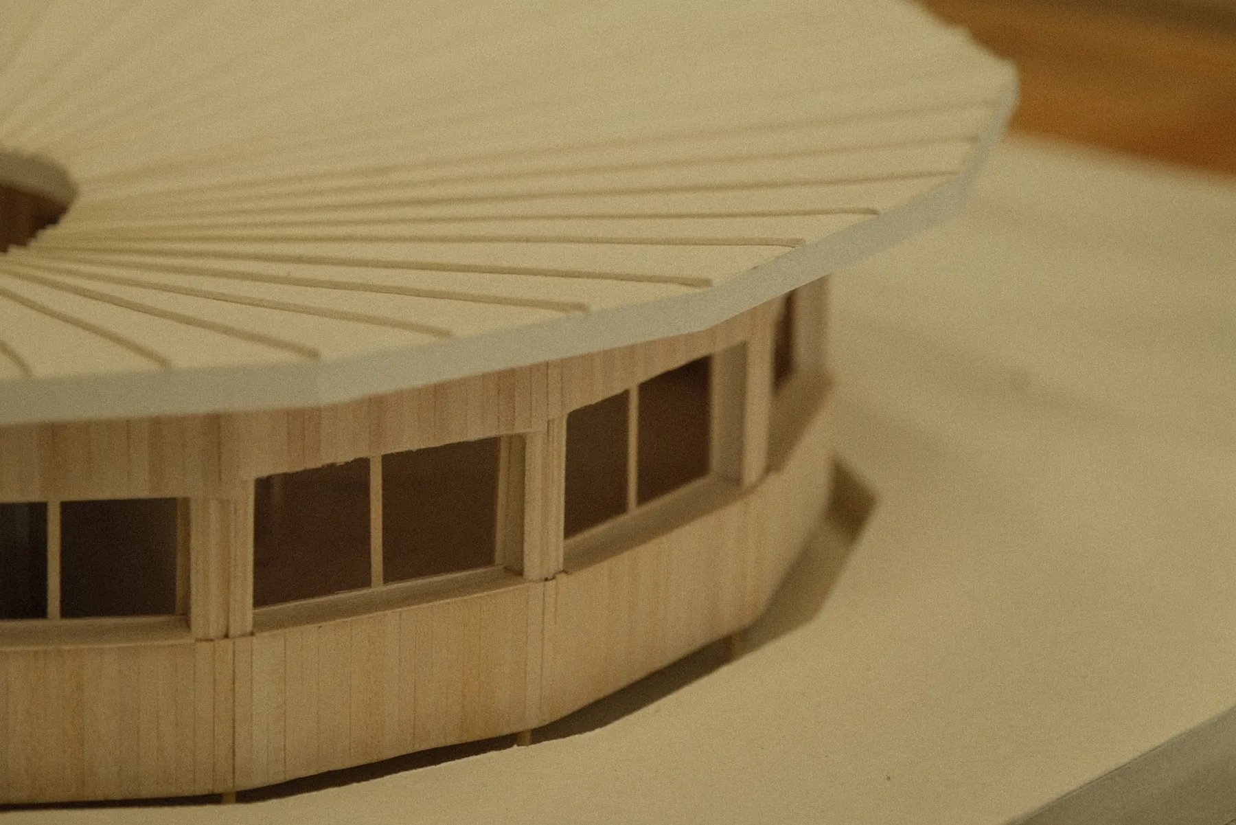 Close view of the model roof edge, showing a thin roof plate overhanging a slatted timber wall with a band of square windows.