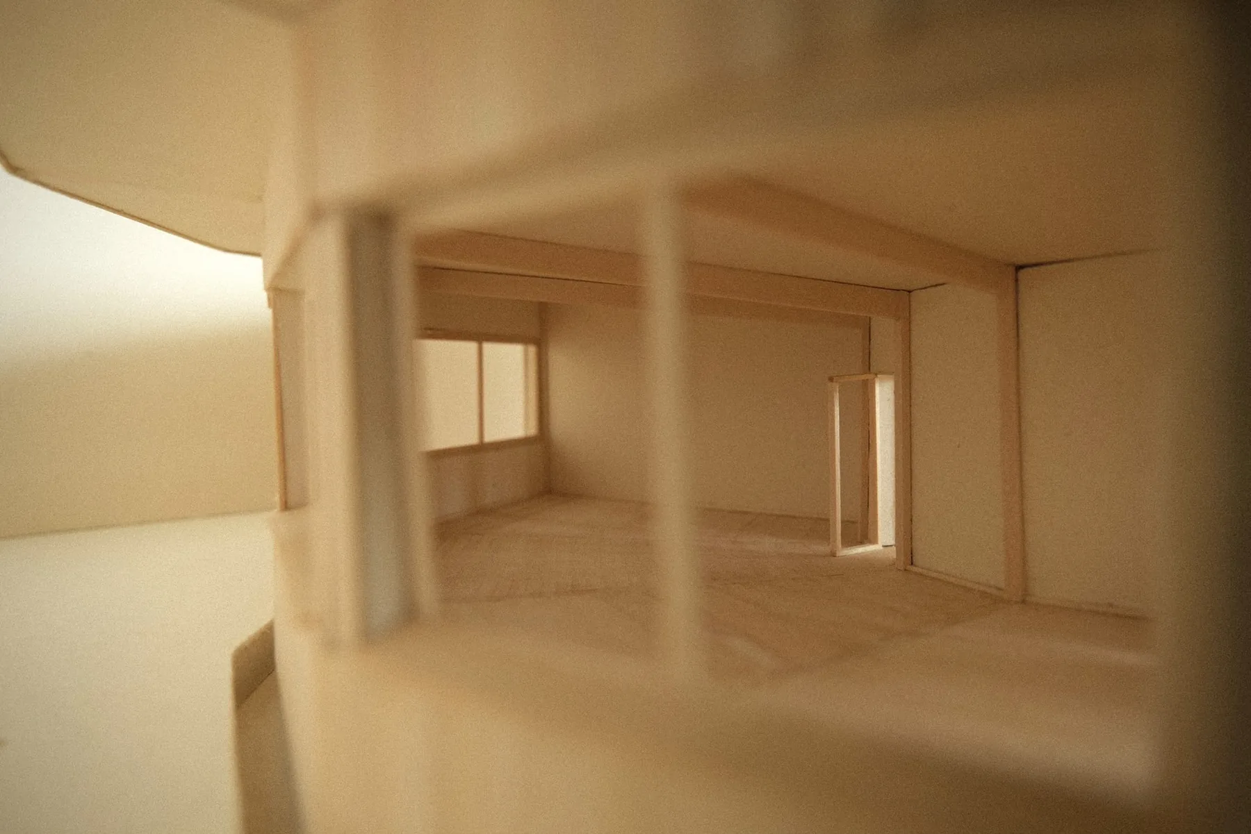 View inside the model through an opening, showing a warm-lit interior with timber posts, beams and a doorway at the far end.
